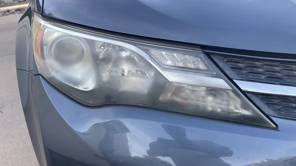 Hazy headlight lens showing surface wear from repeated washing.